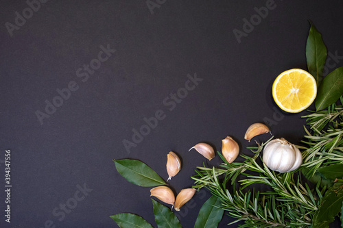Food frame with rosemary sprigs, bay leaves, lemon half and cloves of garlic, design template 