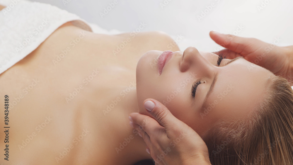 Young, beautiful and healthy woman in massaging salon. Traditional face massage therapy and skin care.