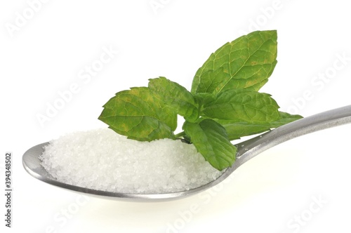 Feuilles de stevia et sucre en poudre dans une cuillère en gros plan sur fond blanc