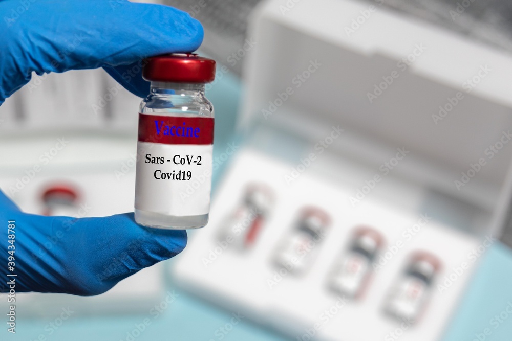 selective focus of a Covid19 vaccine vial held by latex gloves in a hospital selective focus of a Covid19 vaccine vial held by latex gloves in a hospital