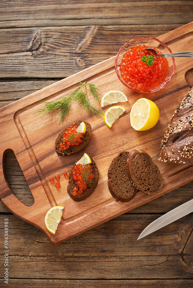 red caviar with black bread, dill and lemon on wooden board red caviar with black bread, dill and lemon on wooden board