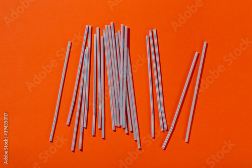 Colored tubules for juice and cocktails on orange background. Space for text.