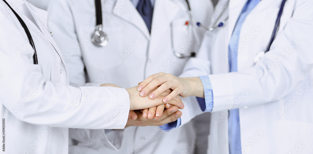 Group of modern doctors joining hands as a circle and ready to help patients. Teamwork in medicine during Coronavirus pandemic. Covid 2019 Group of modern doctors joining hands as a circle and ready to help patients. Teamwork in medicine during Coronavirus pandemic. Covid 2019