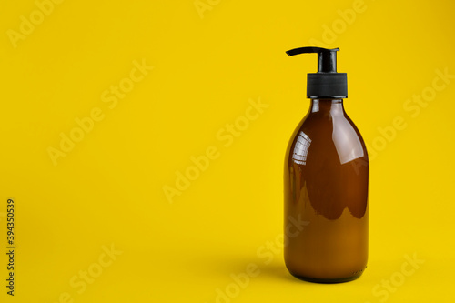Cosmetics containers mockup. Glass cosmetic container with dispenser on a yellow background. Beauty products for body care.