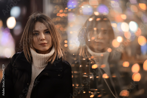 girl christmas lights evening decorated city, a young model on the background of urban decorations and garlands, night city lights
