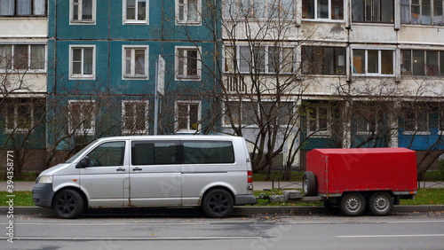 An old wrecked red hatchback car is parked outside the house