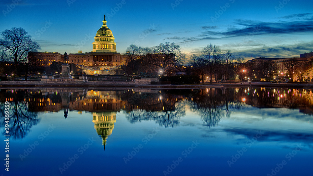 The United States Capitol building at sunset with reflection in water.