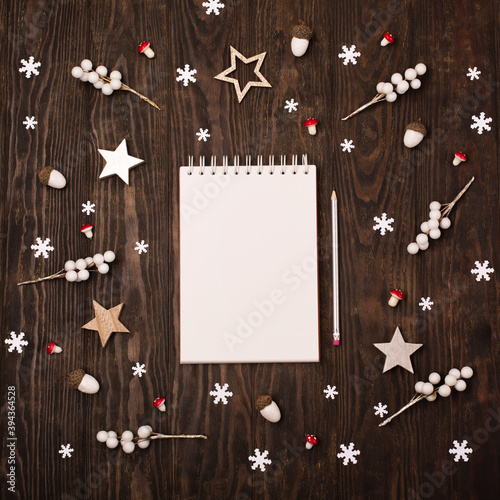 Empty white notebook, Christmas decorations, snowflakes on dark wooden background.