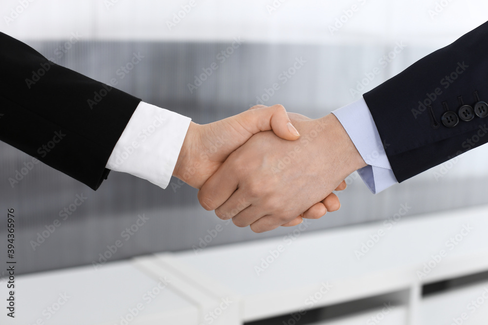 Obraz premium Businessman and woman shaking hands in office. Concept of handshake as success symbol in business