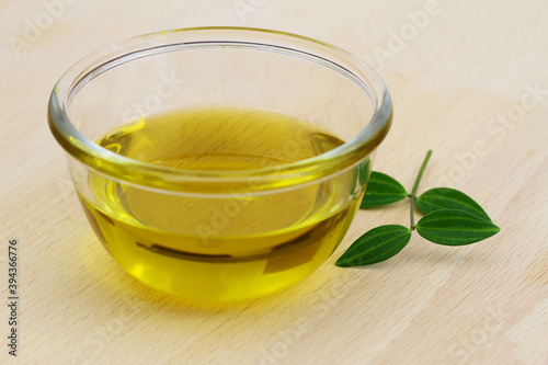 Healthy olive oil in transparent glass bowl on wooden surface 