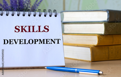 SKILLS DEVELOPMENT - a word in a notebook against the background of old books with a pen