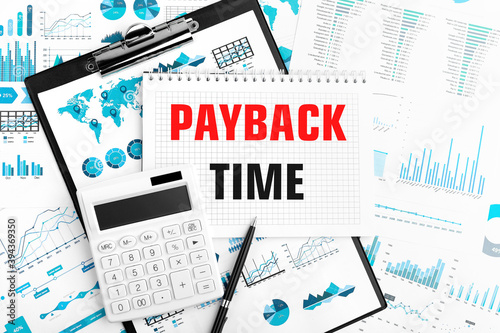 Text PAYBACK TIME on notebook. Calculator, pen, clipboard, charts, documents and graphs on background. Top view.