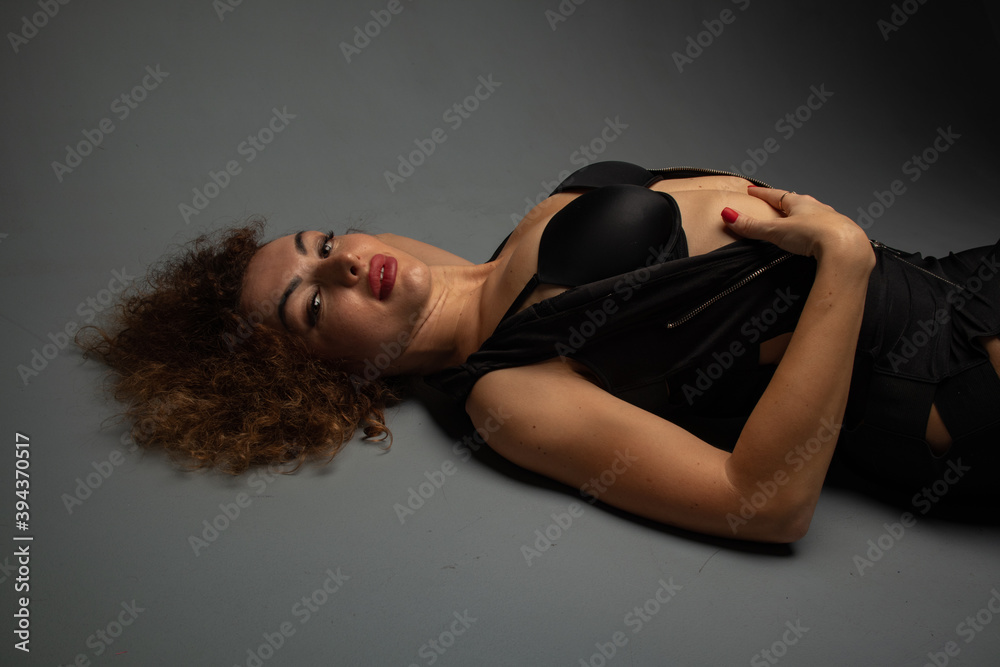 curly girl in black clothes on a gray background in a photo studio curly girl in black clothes on a gray background in a photo studio