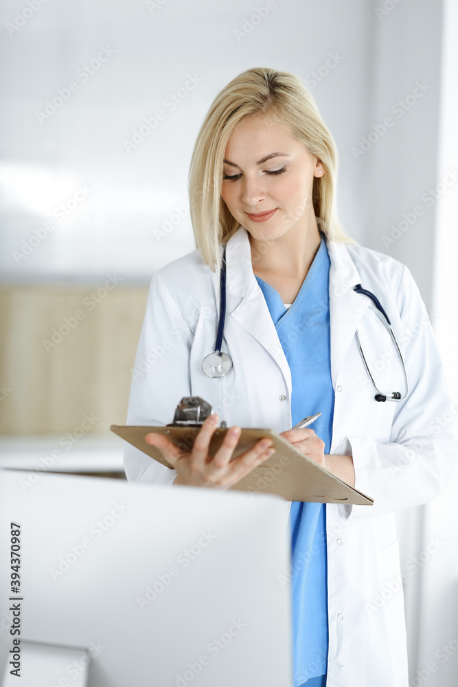Woman-doctor standing in hospital or clinic and filling up medication history record form. Data and best service in medicine and healthcare Woman-doctor standing in hospital or clinic and filling up medication history record form. Data and best service in medicine and healthcare