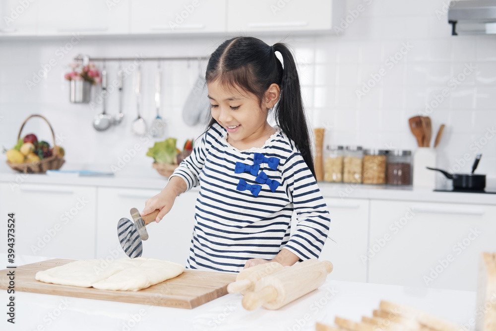 Smiling Asian little asian girl child is learning and enjoying for baking cookies bakery on wooden Cutting board in kitchen. Homemade pastry for bread. Family love and Homeschool. Smiling Asian little asian girl child is learning and enjoying for baking cookies bakery on wooden Cutting board in kitchen. Homemade pastry for bread. Family love and Homeschool.