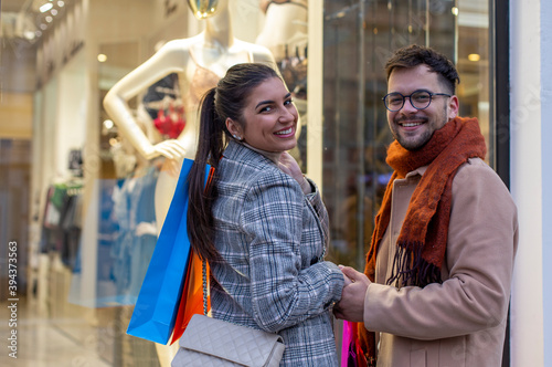 Portrait of couple in shopping in front of the store window.