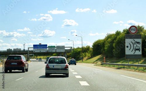 Driving on a highway, with a sign indicating a radar control for the speed limit.