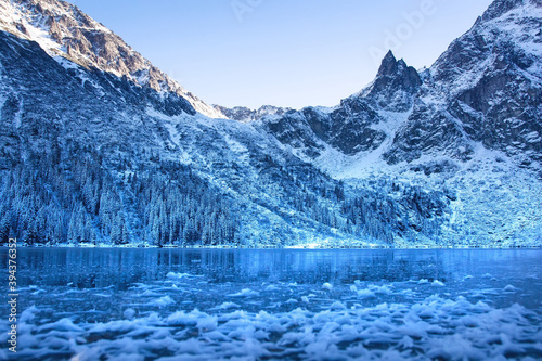 Winter landscape of snowy rocky mountains and ice lake. Winter natural background.