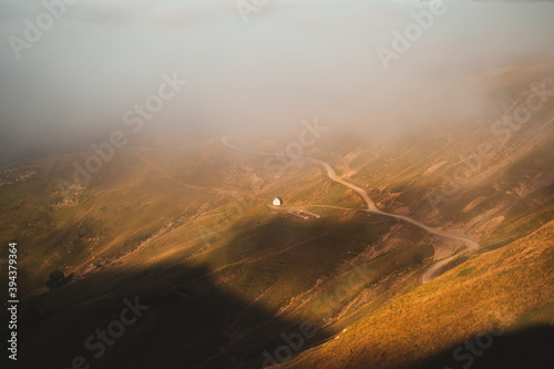 Small cabin beneath the fog next to a gravel path