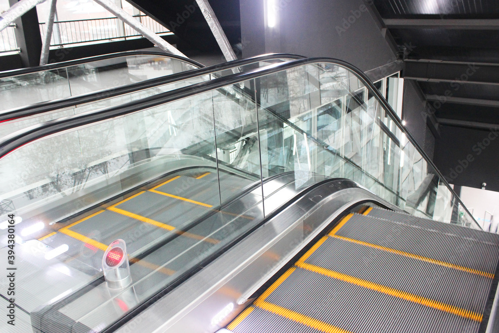 Obraz premium Modern luxury escalators with staircase in a shopping mall Metal excavator with neon lighting with rubber handrails, staircase view, descent to the floor .. Awareness of safety in daily life Modern