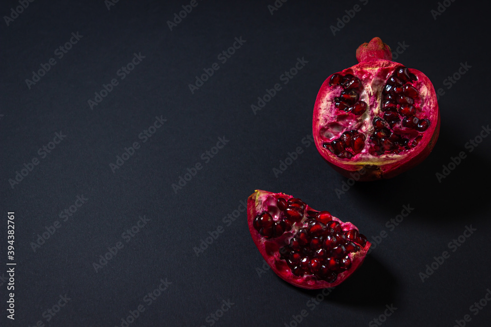 Fototapeta premium Pomegranate on a black background. Cut Pomegranate. Red fruit. Photo from above. There is a place for an inscription or logo