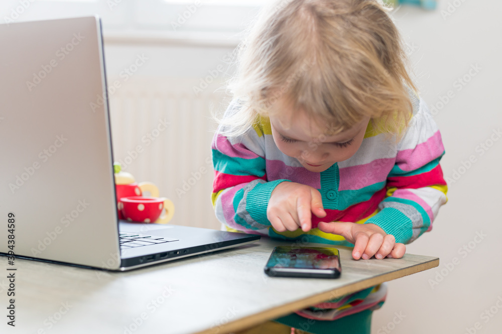 Cute girl using smart phone while working on a computer.