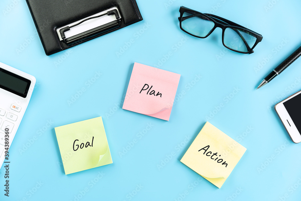Business desk office with Goal, plan and action sticky notes on color background, Top view with copy space Business desk office with Goal, plan and action sticky notes on color background, Top view with copy space
