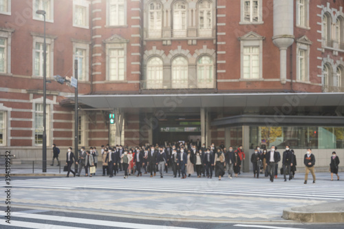 Fototapeta Naklejka Na Ścianę i Meble -  意図的にピントをぼかした東京駅前の横断歩道を渡るマスク姿のビジネスマンたち