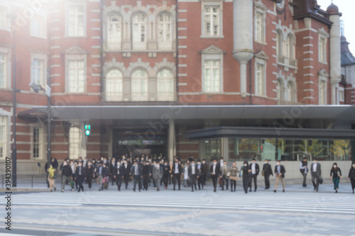 意図的にピントをぼかした東京駅前の横断歩道を渡るマスク姿のビジネスマンたち © paru