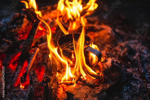 Close up of tea in metal mug heats up in bonfire