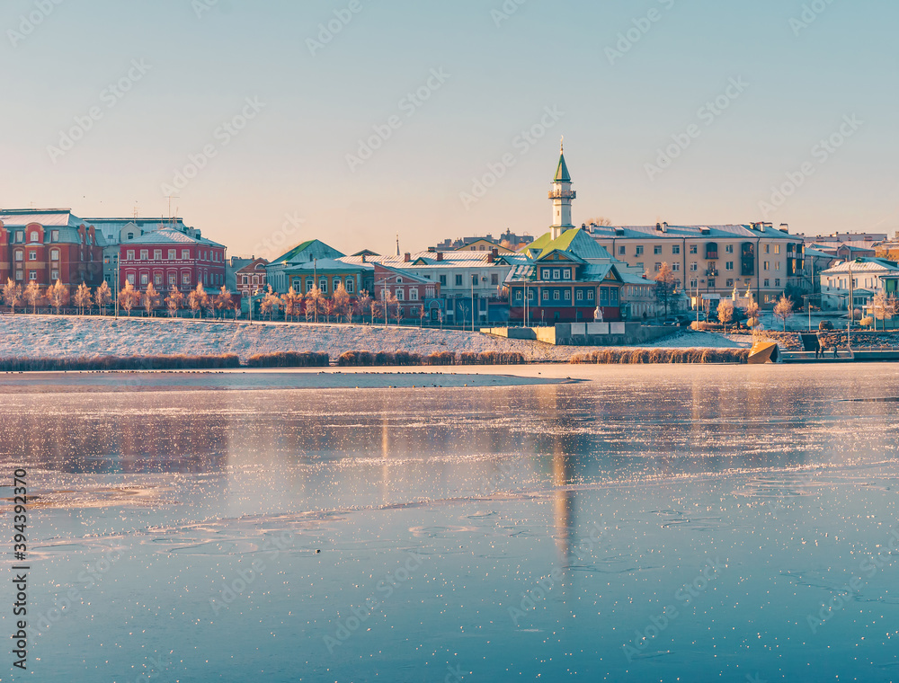 Fototapeta premium Old Tatar district at sunrise in winter. Reflection in the ice of a frozen river. Beautiful view of the city. Lake Kaban and mosques