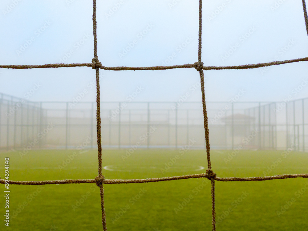 close up football goal net, football field in fog close up football goal net, football field in fog