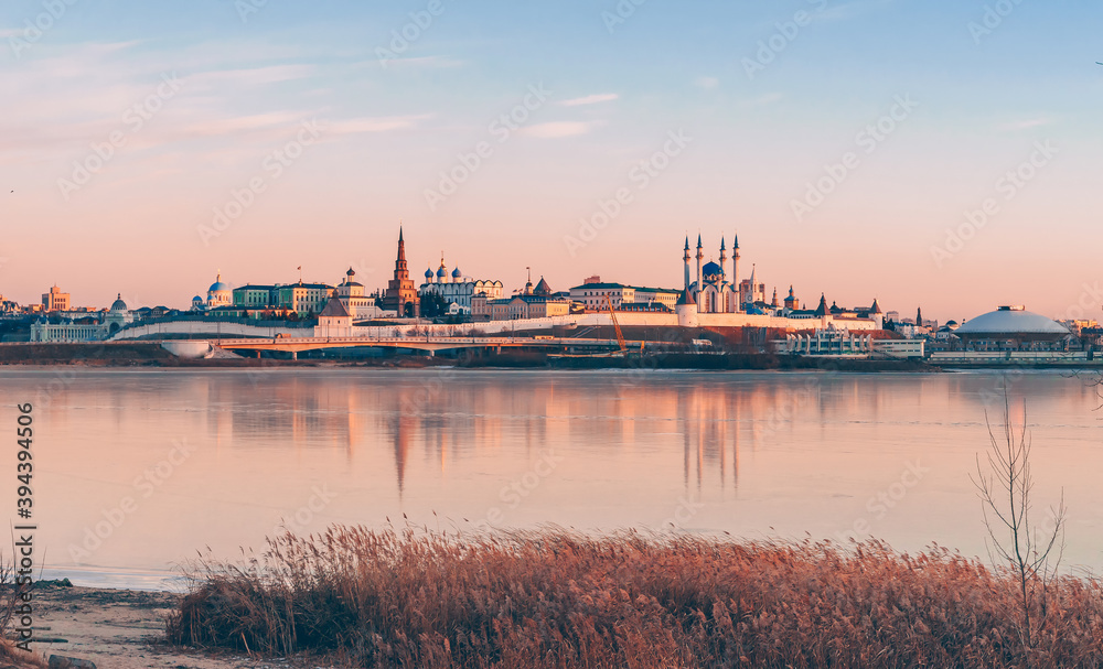 Obraz premium The Kazan Kremlin at sunset in winter. Reflection in the ice of a frozen river. Beautiful view of the city
