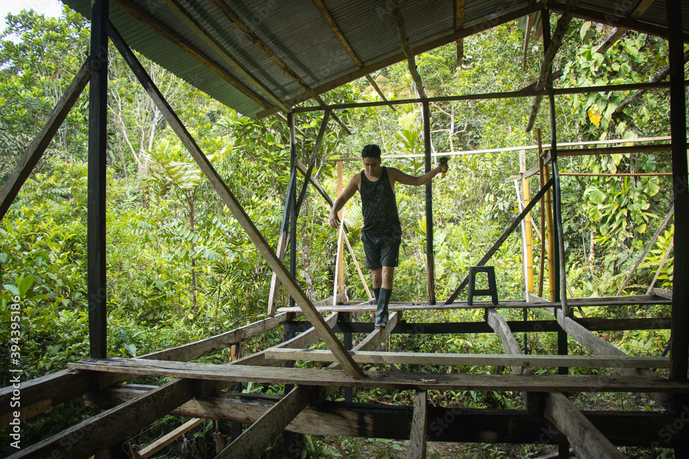 Hombre joven haciendo equilibrio en una construcción de una casa en medio de la naturaleza Hombre joven haciendo equilibrio en una construcción de una casa en medio de la naturaleza