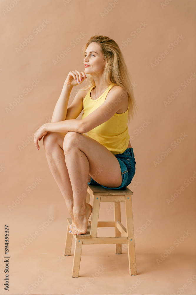 Fototapeta premium Beautiful young blonde model in casual clothes posing on stepladder