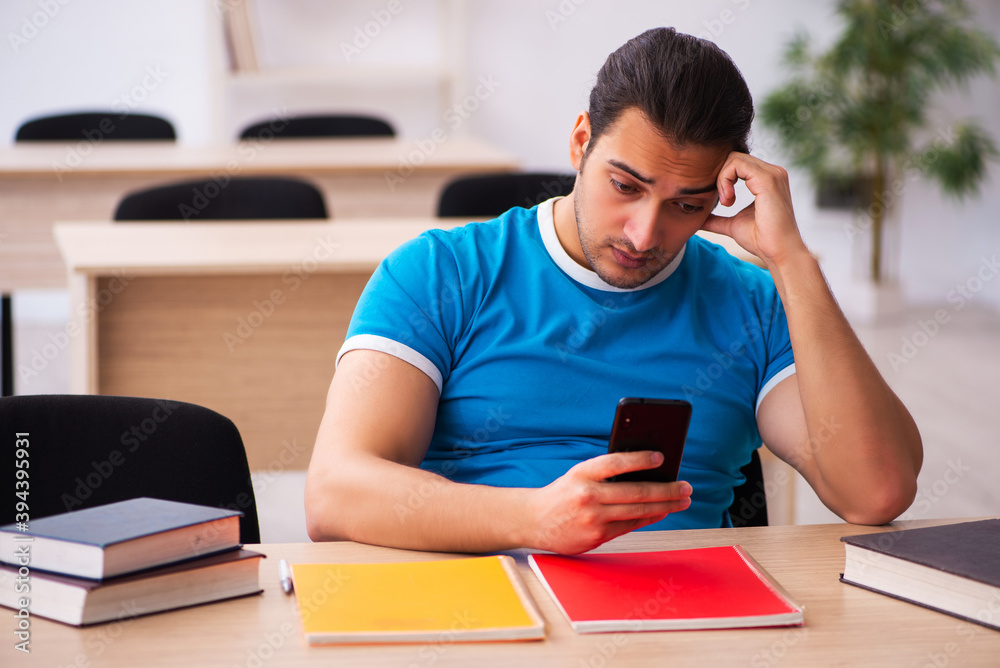 Exhausted male student preparing for the exams in the classroom Exhausted male student preparing for the exams in the classroom
