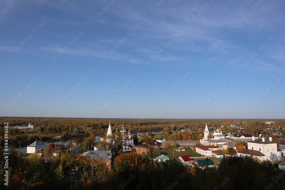 Naklejka premium Beautiful autumn panorama, landscape, top view, Vladimir city, Russia. Stunning autumn landscape, top view, sun and blue sky, yellow trees, white Church, Golden domes, green grass, red leaves. Park. 