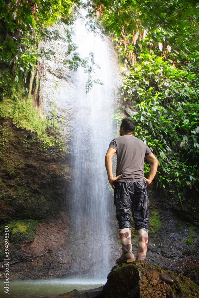 Hombre en una cascada de agua natural en la selva