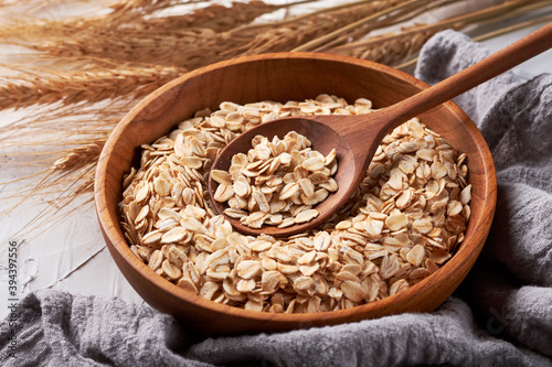 Rolled oats or oat flakes in bowl with wooden spoon background