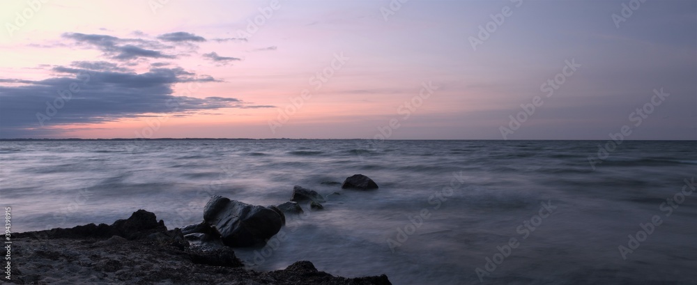 Obraz premium panoramic view to rocks by the sea at dawn, long exposure