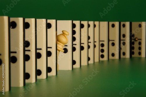 Pieza de ajedrez asomando entre una fila de fichas de dominó