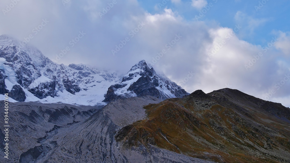 Panoramic view of the eastern flank of the majestic Ortler mountains in the Alps with glacier Suldenferner on a cloudy day in autumn near Sulden in South Tyrol, Italy in autumn season.