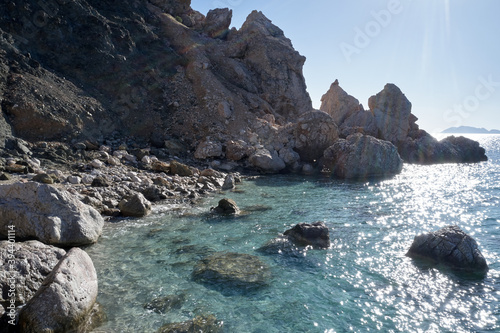 Sea shore with rocks and transparent clear sea water. Sea water surface with ripple and sun reflection sparkles. Natural marine background.