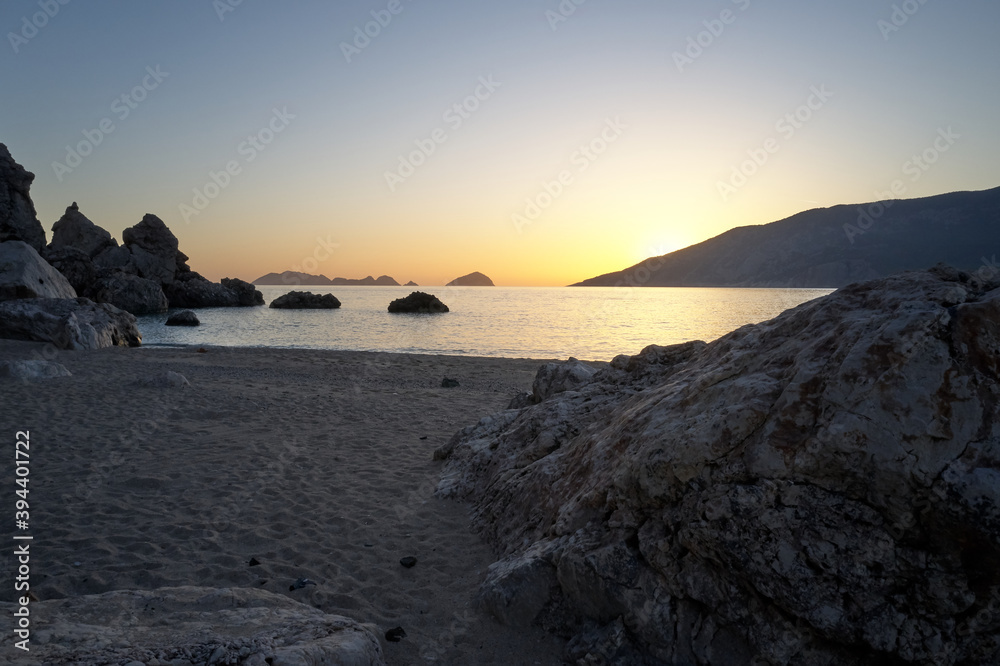 Picturesque seascape with rocky cliffs at sunset. Sandy beach with rocks and view to calm sea in the evening. Scenic view of beautiful sea landscape.