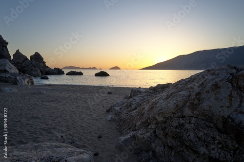 Picturesque seascape with rocky cliffs at sunset. Sandy beach with rocks and view to calm sea in the evening. Scenic view of beautiful sea landscape.