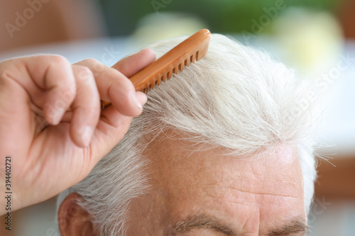 Senior man combing his hair...