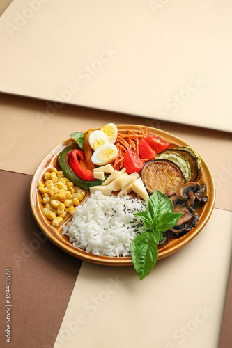 Plate of delicious rice salad with vegetables on color background
