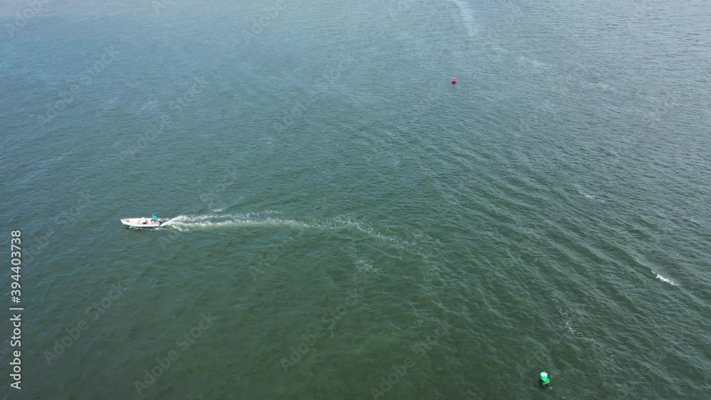 An aerial drone view over Jones Inlet on a sunny day. The camera hovers in place & focuses on a small boat just turning around. An aerial drone view over Jones Inlet on a sunny day. The camera hovers in place & focuses on a small boat just turning around.