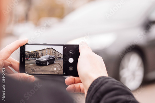 a man takes pictures of a car on the phone in the middle of the city