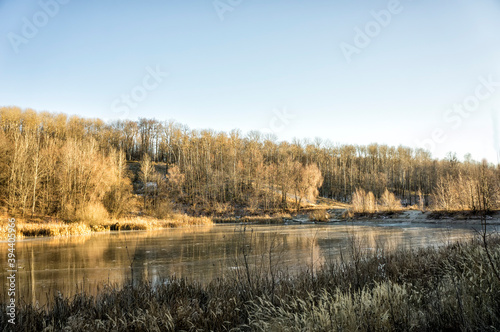 Autumn landscape with a brightly lit forest and a frozen pond